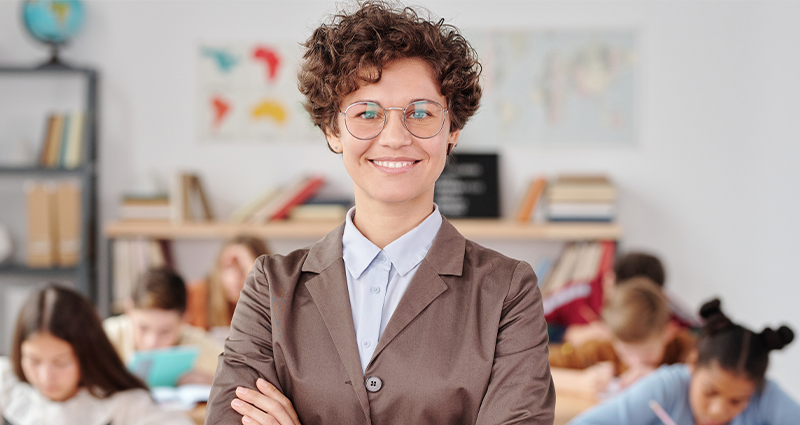 Stock photo of a teacher smiling at the camera. From Max Fischer on Pexels.