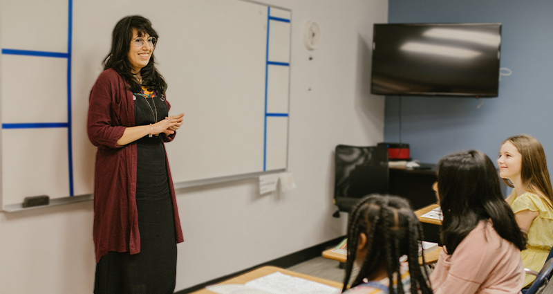 Stock photo of a teacher talking to students in her classroom by Rodnae Productions on Pexels.
