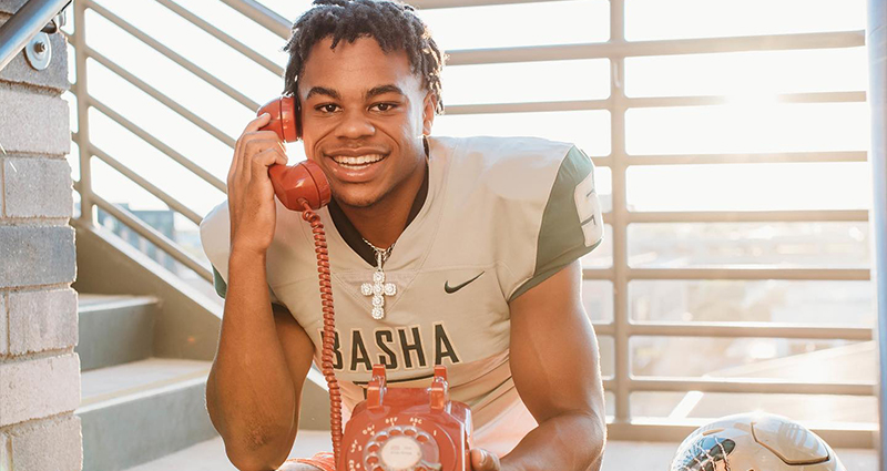 Photo of a Basha High School football player miming answering a corded phone.