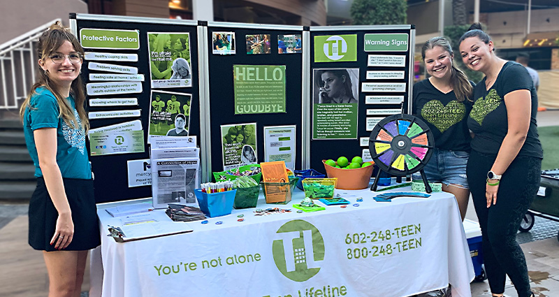 Photo of Teen Lifeline Crisis Service Associate Madison Marks running a resource booth with teen peer counselors at the 2022 Teen Suicide Prevention Month Rally.