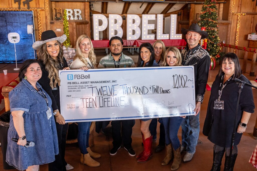 Photo of PB Bell handing a large check for ,002 to Teen Lifeline Fund Development Specialist Luis Barcelo.