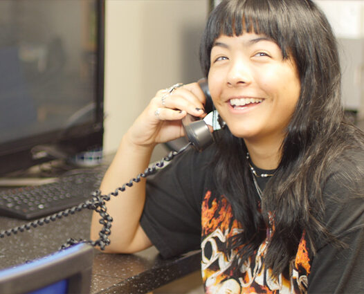 Stock photo of a teen peer counselor smiling while on a hotline call.