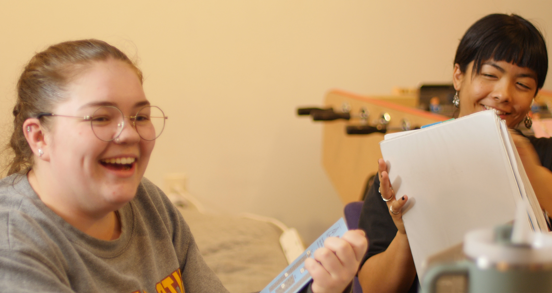 Photo of two teen peer counselors laughing and smiling while working on homework.